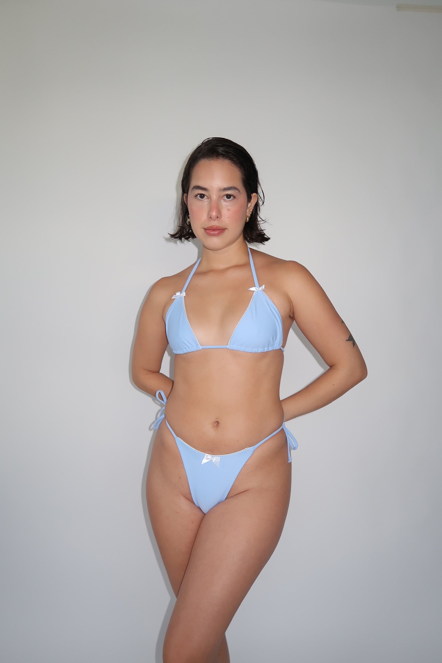 Pretty teenage girl wearing blue bikini in front of white